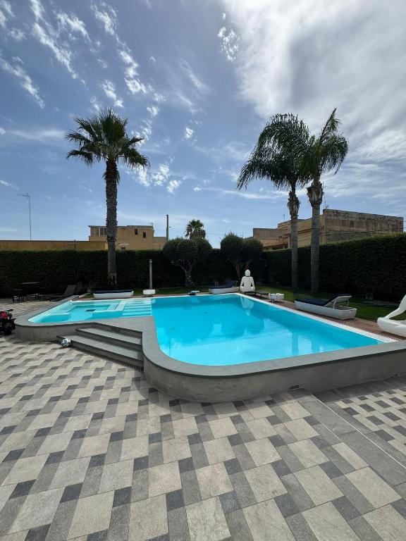 a large swimming pool with palm trees in the background at Villa Panama con piscina - Mazara del vallo in Mazara del Vallo