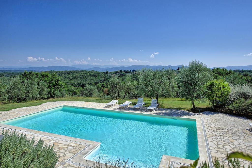 una piscina in un cortile con sedie e alberi di Pozzo Dei Desideri by PosarelliVillas a Mercatale Val Di Pesa