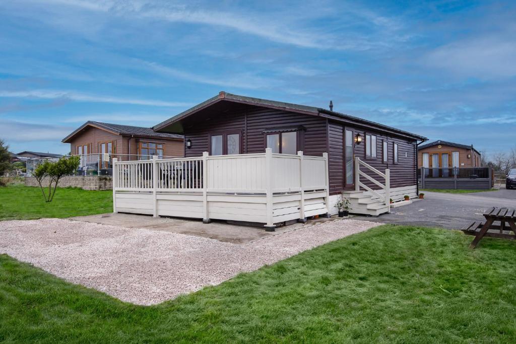 a house with a white fence in a yard at Tranquil Lodge with river views in Hambleton