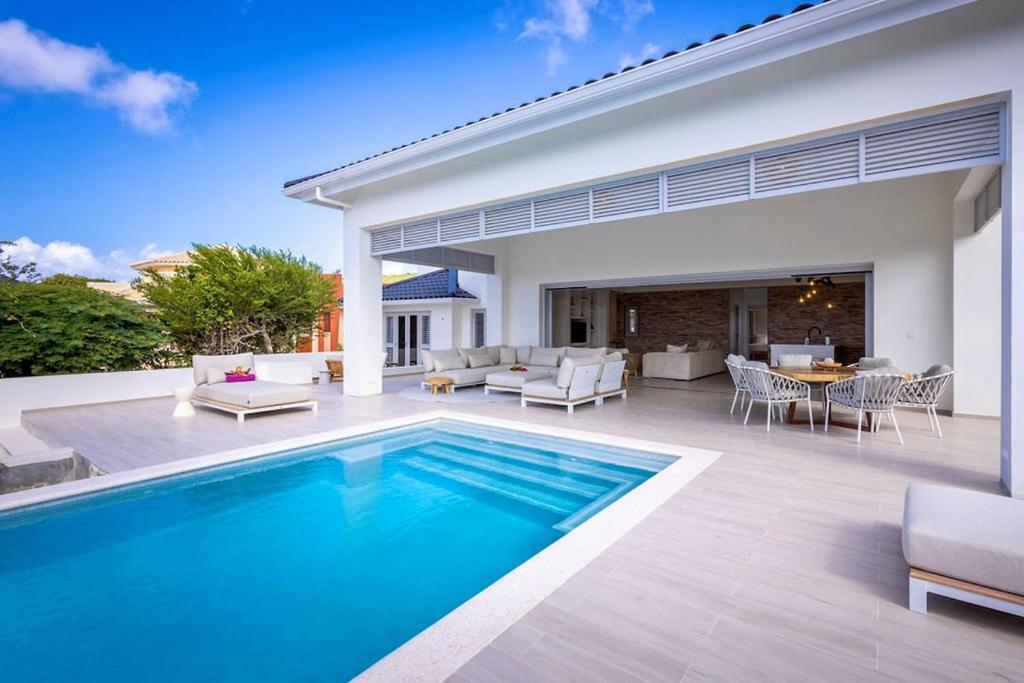 a swimming pool in front of a house at Villa Flores Corales 84 - Coral Estate in Willibrordus