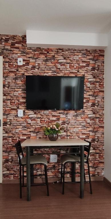 a television on a brick wall with a table and chairs at Doce Encanto in Uberaba