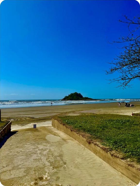 a sandy beach with a bench and people on the beach at Casa de temporada enfrente a praia in Itanhaém