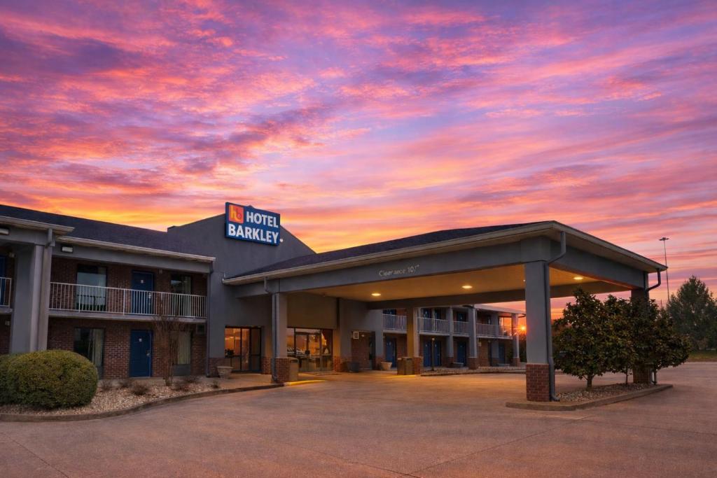 a hotel courtyard with a sunset in the sky at Hotel Barkley in Kuttawa