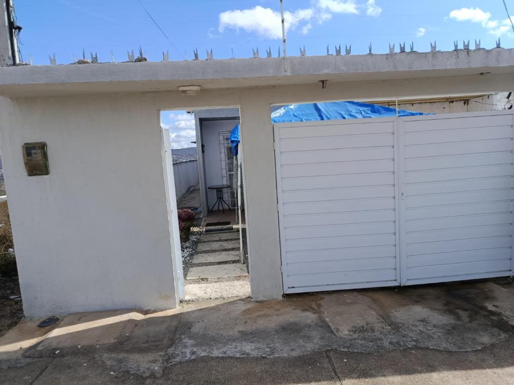 a garage with a white door and a gate at Alameda Jardim Serra Negra in Bezerros