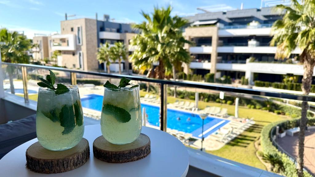 two cocktails on a table with a view of a pool at MG Playa Flamenca Village in Orihuela Costa
