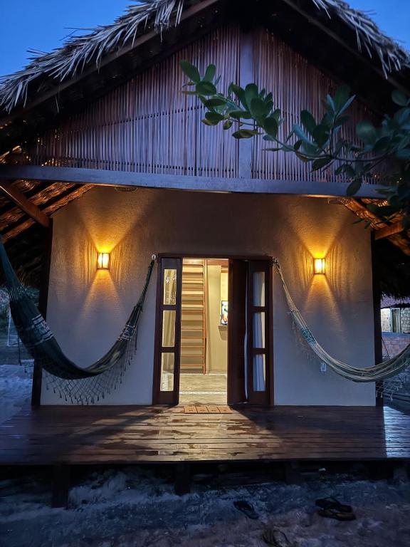 a house with a hammock in front of it at Dell Ville Cabin in Barreirinhas