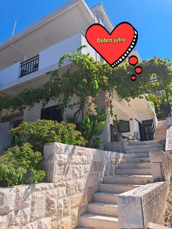 a house with a heart sign in front of it at Rooms Katja in Gradac
