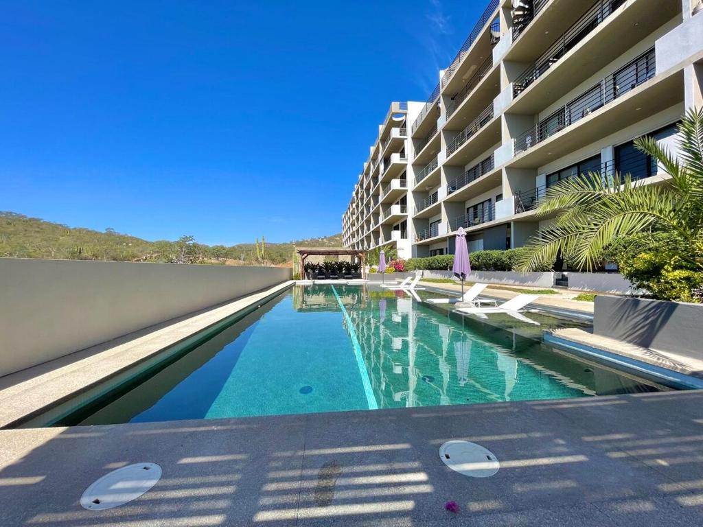 a swimming pool in front of a building at Marea Sabina Luxury Ocean View & Amenities in Cabo San Lucas