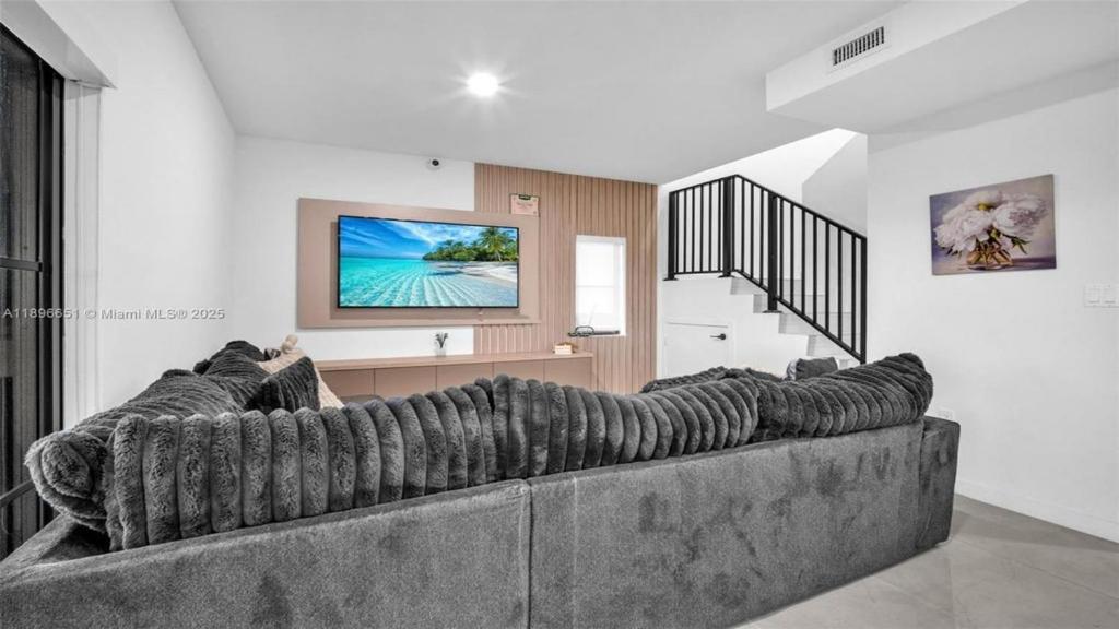 a living room with a large couch and a tv at La casita tropical in Florida City