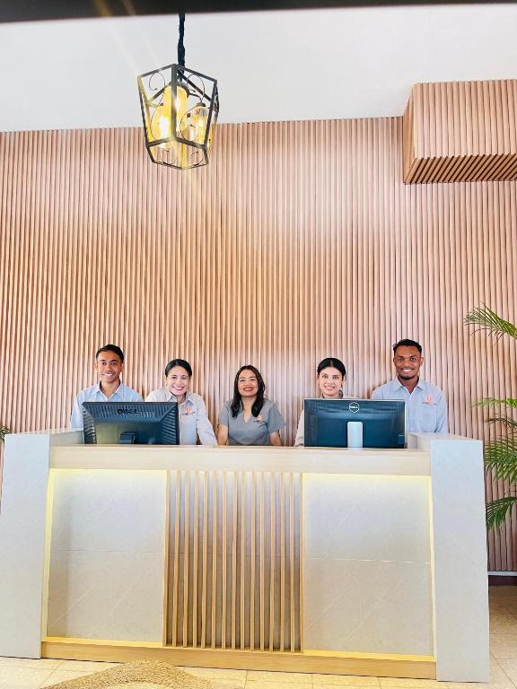 a group of people standing behind a desk with computers at Sunset INN by Pro-Ema in Dili