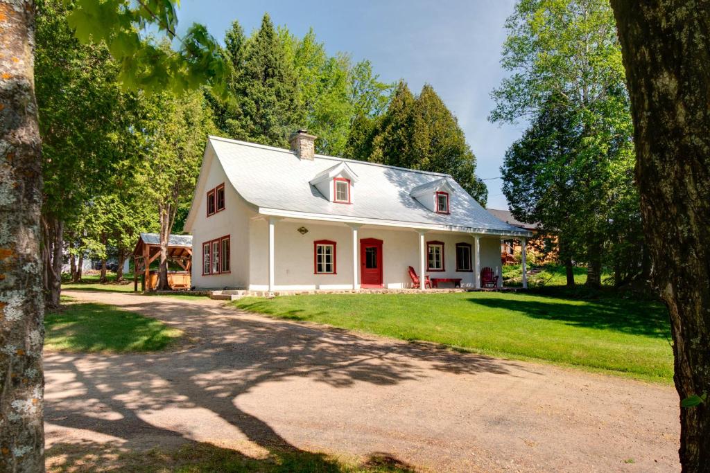 a white house with a red door at Maison Bilodeau Ethier - 5 chambres - 13 personnes in Saint-Férréol-les-Neiges