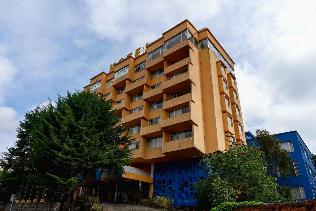 a tall building with a tree in front of it at Hotel Savoy Inn in Quito