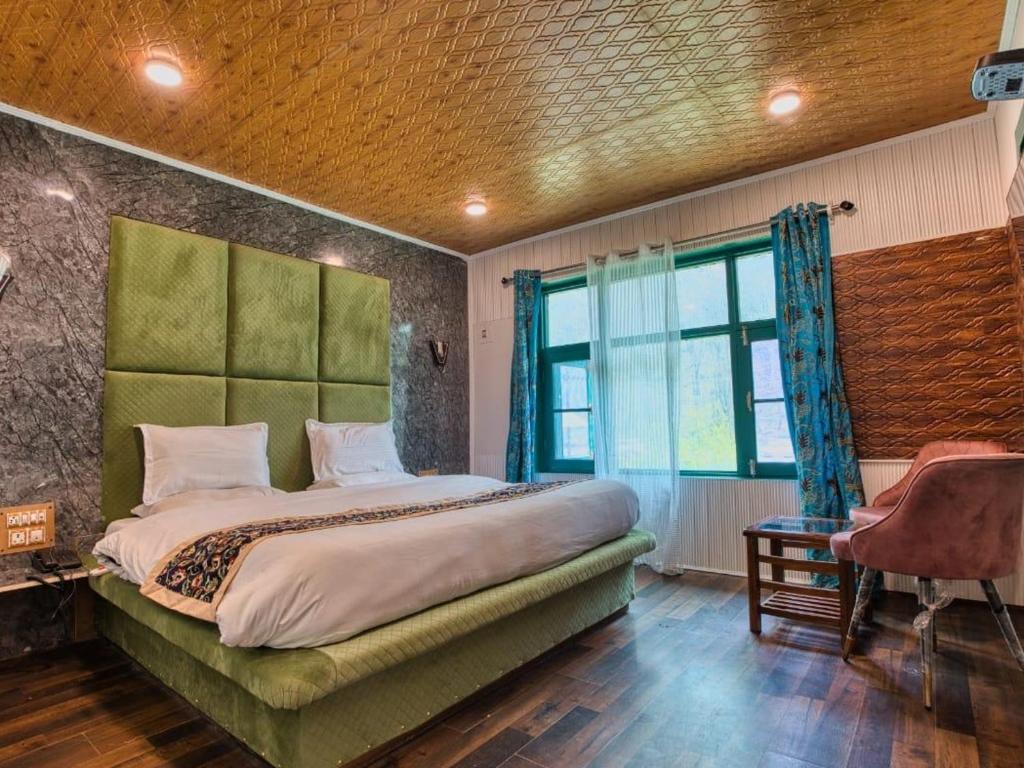 a bedroom with a bed with a green headboard and a window at D’SHIEKHS RESORT GUREZ in Kanzalwan