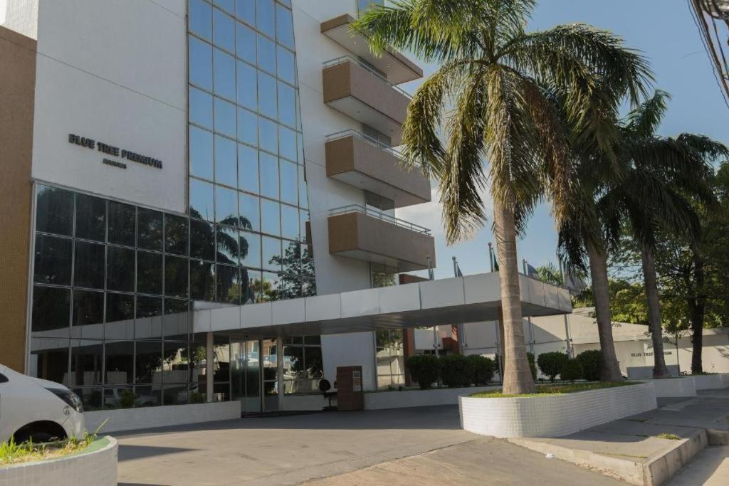 a building with a palm tree in front of it at Flat Premium Manaus no Adrianópolis in Manaus