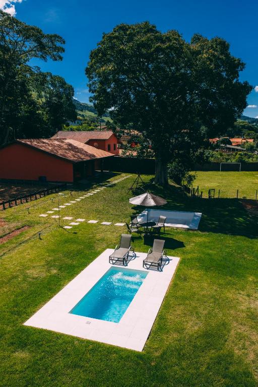 a swimming pool with two lounge chairs and a tree at Paineira Vila Flat in Paraisópolis