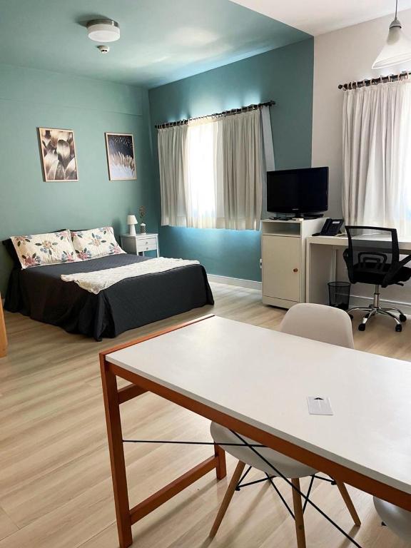 a bedroom with a bed and a desk and a table at Flat Hotel Confort Suítes Alphaville in Barueri
