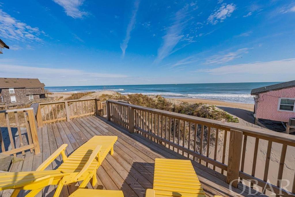 a deck with yellow chairs and a view of the beach at Nautical Endeavors Beach House Steps from Surf in Rodanthe