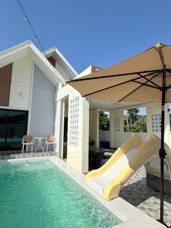 a pool with a slide and an umbrella at MBP Pool villa เอ็มบีพี พูลวิลล่ายะลา in Changwat Yala