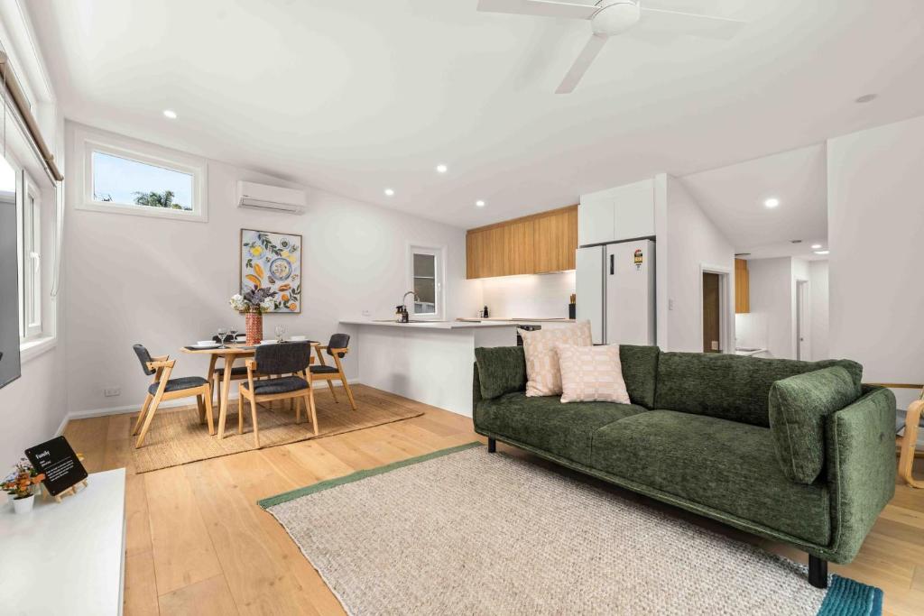 a living room with a green couch and a table at Blenheim Breeze by Experience Jervis Bay in Vincentia