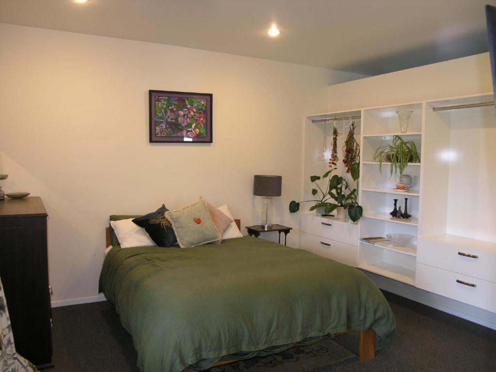 a bedroom with a bed with a green bedspread at Woodhey Retreat Unit 2 in Karapiro