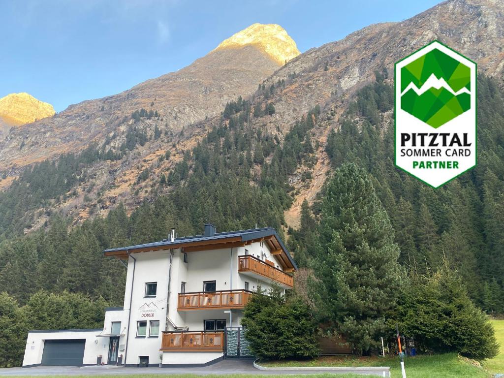 a building with a sign in front of a mountain at Appartements Dobler - s'Darhuam in Sankt Leonhard im Pitztal