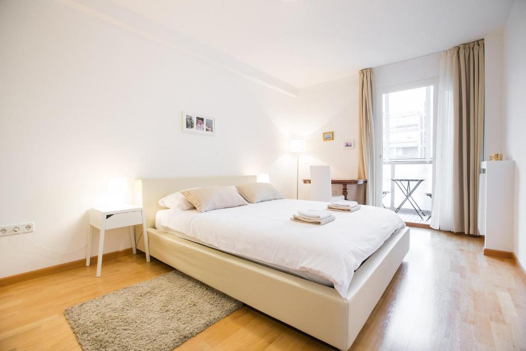 a white bedroom with a white bed and a window at Apartman Kris in Zagreb