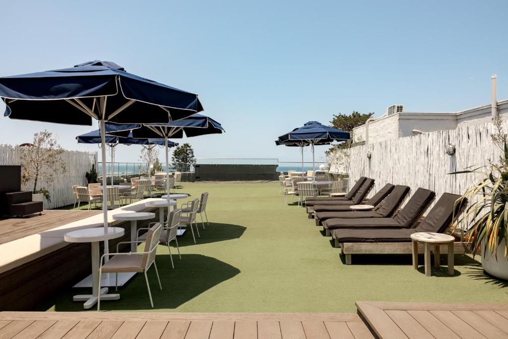 a row of tables and chairs with umbrellas on a patio at Wake Up! Bondi Beach in Sydney