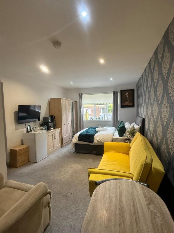 a bedroom with two beds and a yellow couch at Eastern Bridge House in Spinney Hill