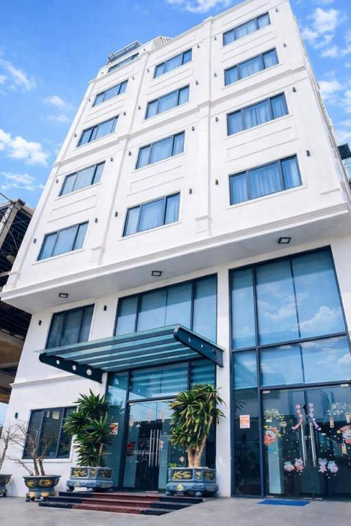 a white building with palm trees in front of it at HT Hotel in Xuyên Mộc