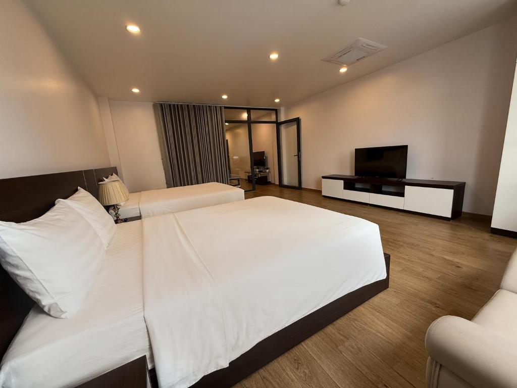 a bedroom with two beds and a flat screen tv at The Nova Hotel & Apartment in Hai Phong