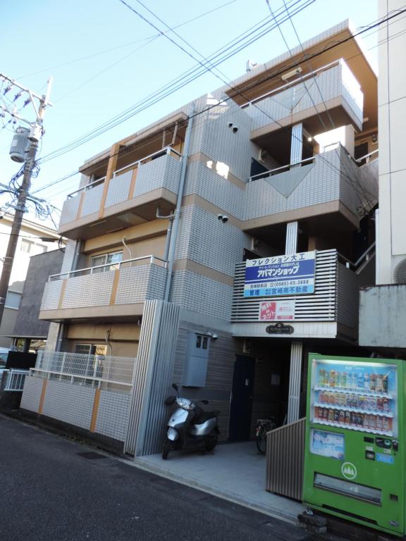 a building with a scooter parked in front of it at フレクション大工町 in Miyazaki