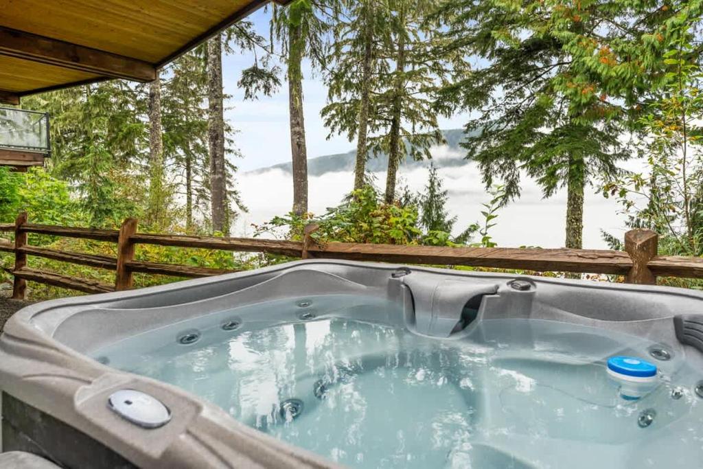 a jacuzzi tub in a backyard with trees at Seaside Haven -Hot Tub with Oceanfront View in Port Renfrew