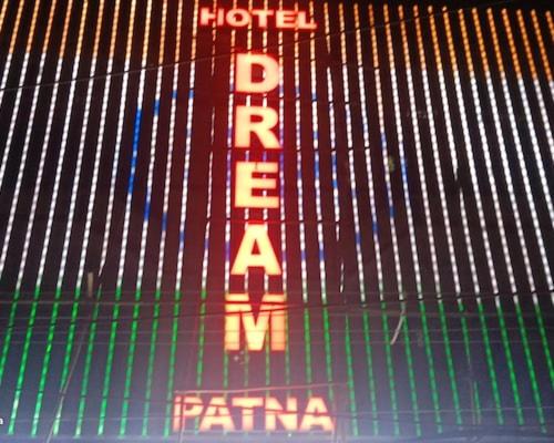 a sign on a fence with a hotel sign on it at Hotel Dream Patna in Patna