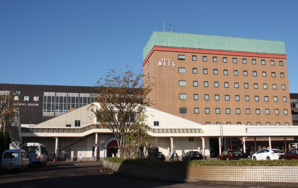 a large building with a lot of cars in a parking lot at Hotel Mets Nagaoka in Nagaoka