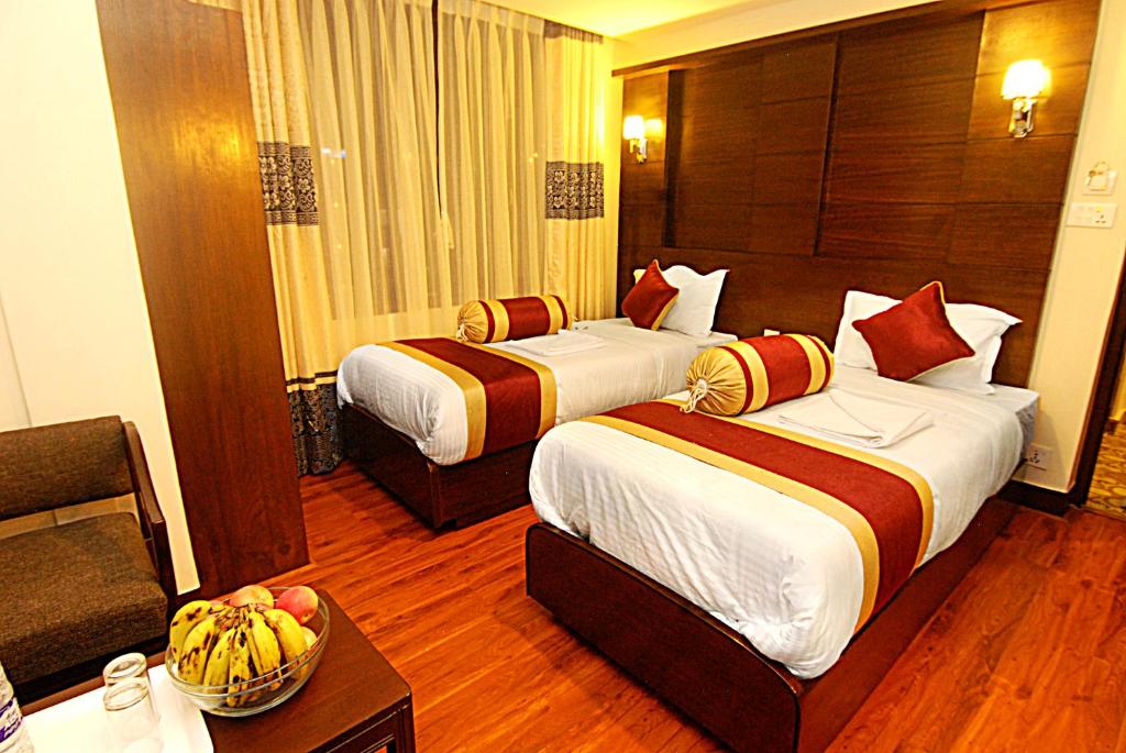 Habitación de hotel con 2 camas y mesa en Hotel Buddha, en Katmandú