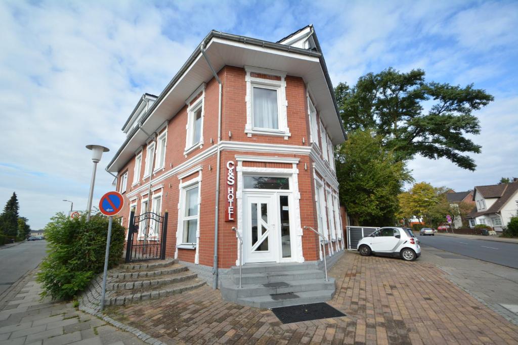 a red brick house with a car parked in front of it at C&S Hotel in Pinneberg