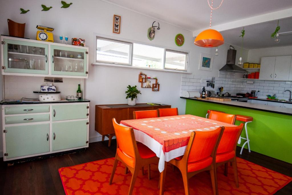 a kitchen with a table and some orange chairs at Eco Retro Aldinga Beach House in Aldinga Beach
