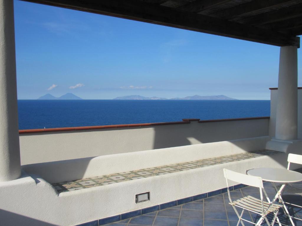 Un balcón con una cama y dos sillas y el océano en Magico Appartamenti Scafa - Marina Capo d'Orlando, en Capo dʼOrlando