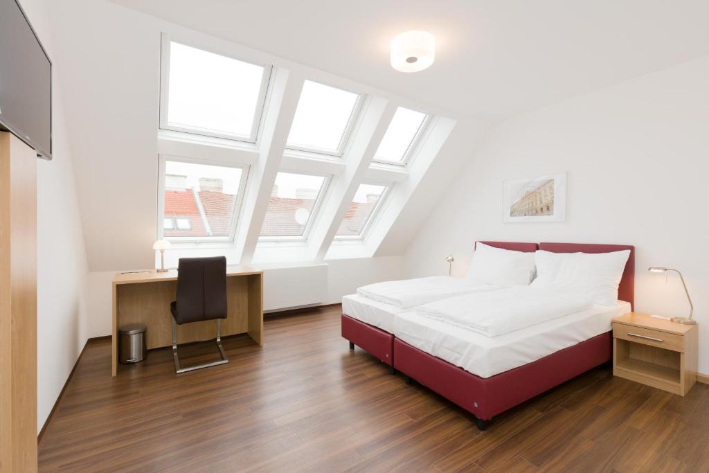 a bedroom with a bed and a desk and windows at Vienna Stay Apartments or Rooms 1050 in Vienna