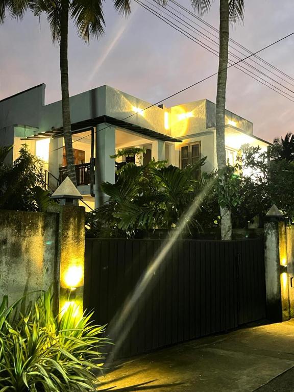 a house with a fence and palm trees at night at Green Sapphire Home Stay in Anuradhapura