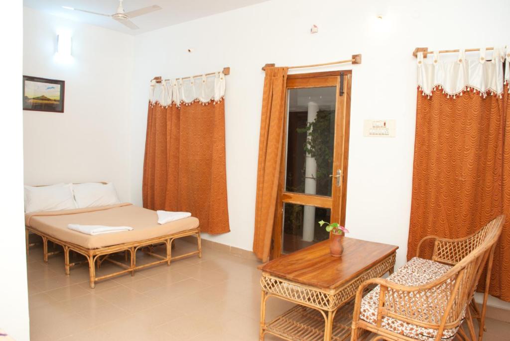 a room with a bed and a table and chairs at The Mountain Retreat in Tiruvannāmalai
