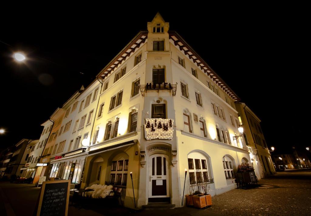 un gran edificio blanco con una torre de reloj por la noche en Hotel Albani, en Winterthur