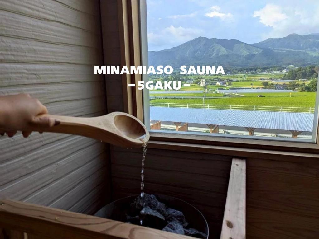 a person is pouring water from a wooden spoon at 南阿蘇サウナ5gaku G1 in Minami Aso