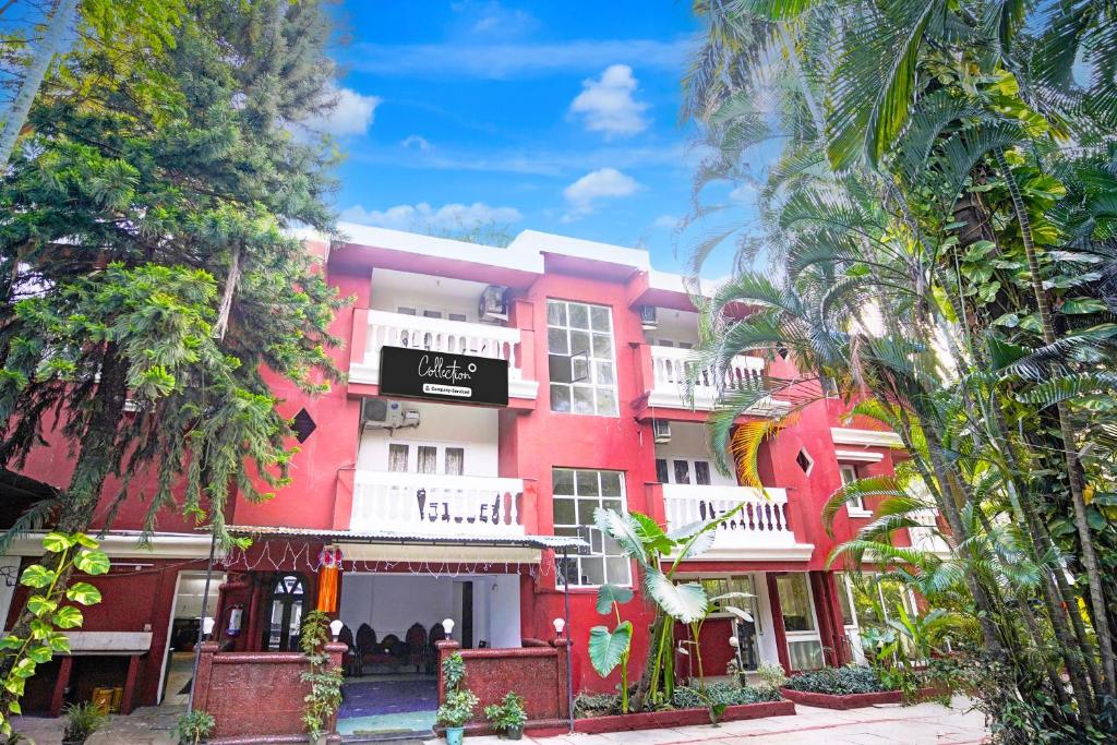 a red building with white balconies and trees at Super Collection O Holiday Street Calangute Formerly Shruti Resort in Goa