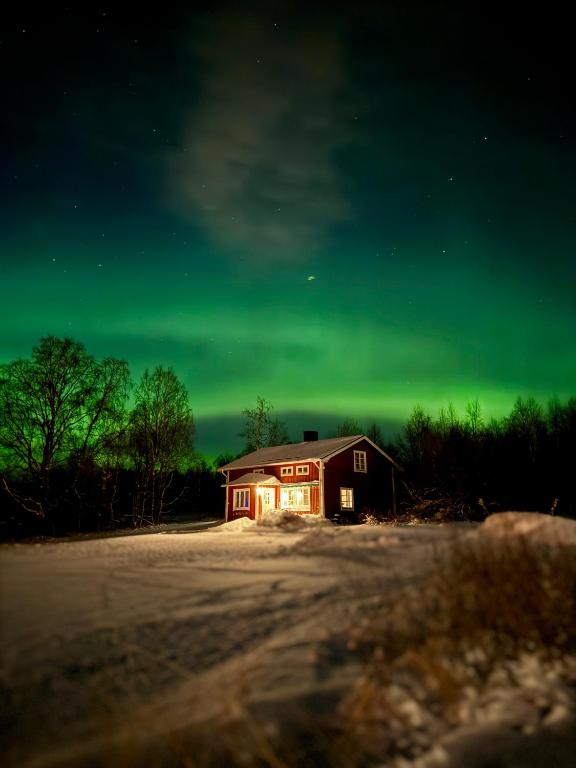 a house with a green sky in front of a barn at Gasabäck Holiday Accomondation in Söråker