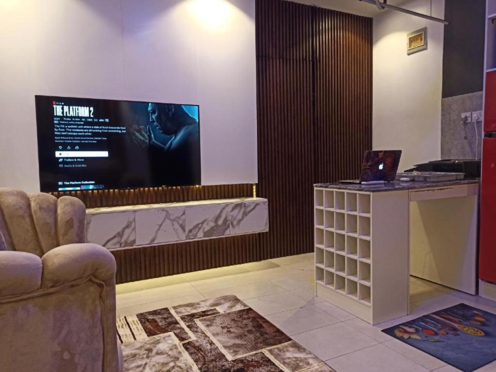 a room with a tv and a chair and a table at Delight 1 Bedroom Apartment - Off Awolowo Road Ikeja in Ikeja