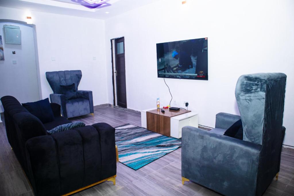 a living room with two chairs and a flat screen tv at Shepherd Spring Apartments in Gbogije