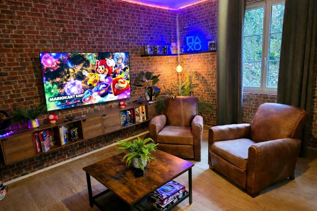 a living room with a tv and a brick wall at L atelier des jeux in Beauvais