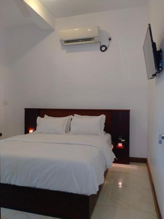 a bedroom with a white bed and a air conditioner at Dilvilla in Nikawatawana