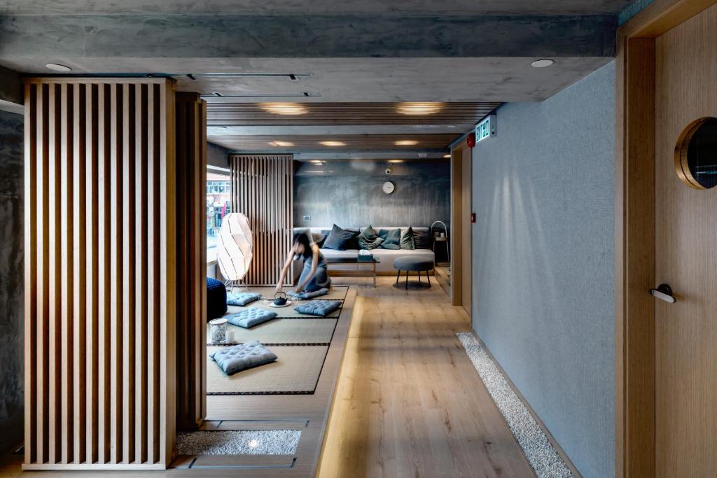 a woman sitting on a couch in a living room at Oootopia Tai Kok Tsui in Hong Kong